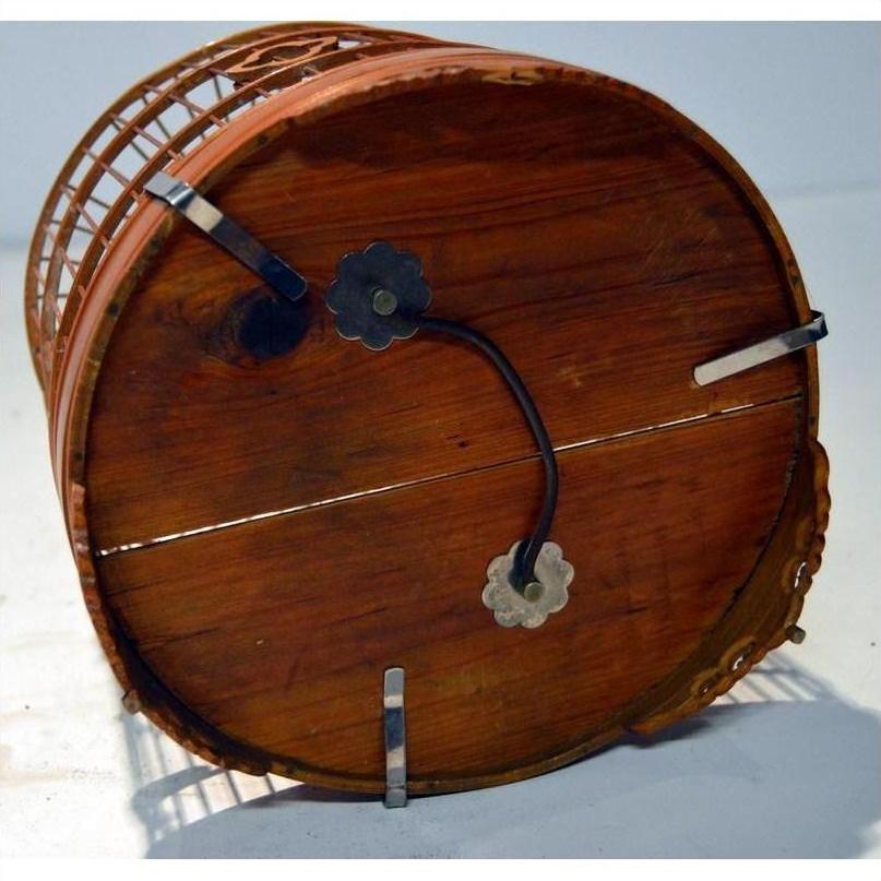 Brown wooden and metal antique Chinese bird cage with circular base and handle, resting on its side.