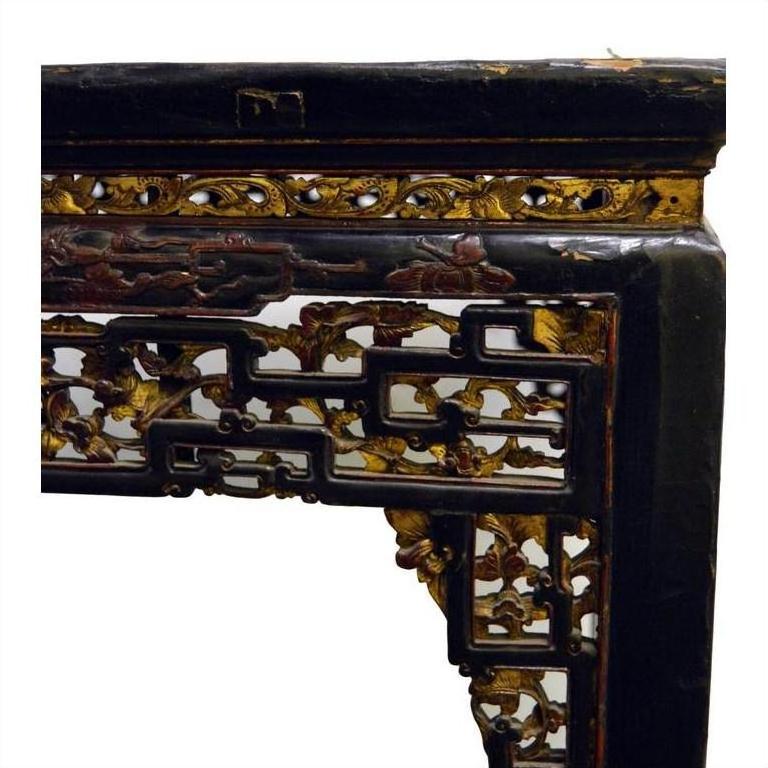 Black lacquered Chinese altar table with hand-carved floral and geometric designs, gold and red accent details.