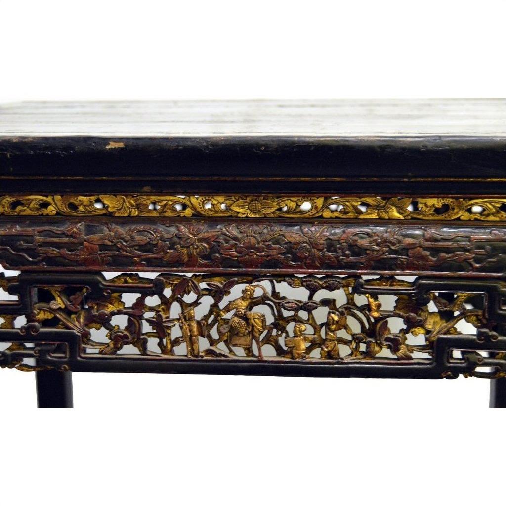 Black lacquered carved wood Chinese altar table with gold and red floral and human motifs on the apron.