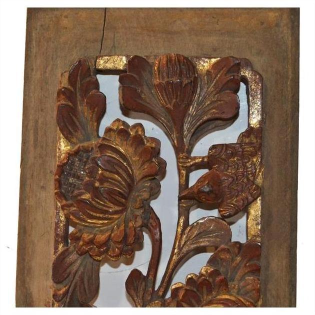 Close-up of antique carved wooden panel with gold accents, floral and bird motifs, intricate detailing.