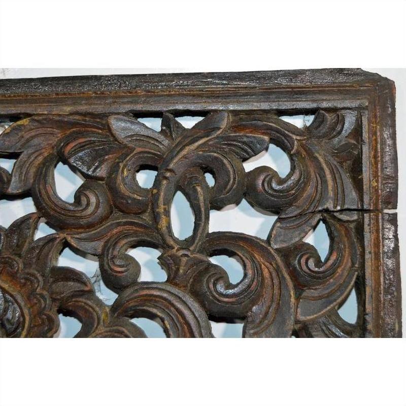 Close-up of brown teak floral lattice panel with antique Chinese carving, swirling patterns, and a right-side crack.