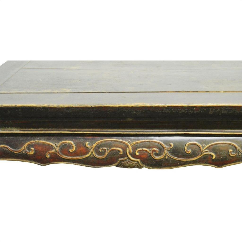 Close-up of antique Indonesian carved wood table edge with ornate hand-carved and painted decorative patterns.