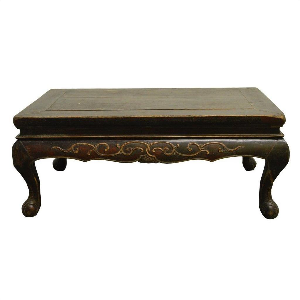 Close-up of dark wood Indonesian carved table with gold accents and curved, hand-carved lion’s paw legs.