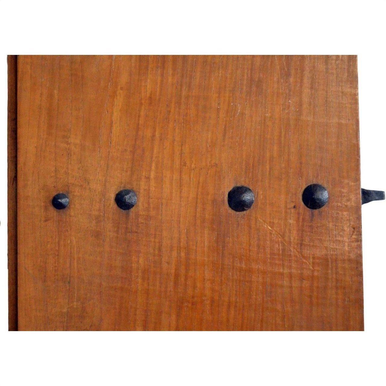 Close-up of antique wooden Chinese door with natural patina, featuring four black metal studs in a row.