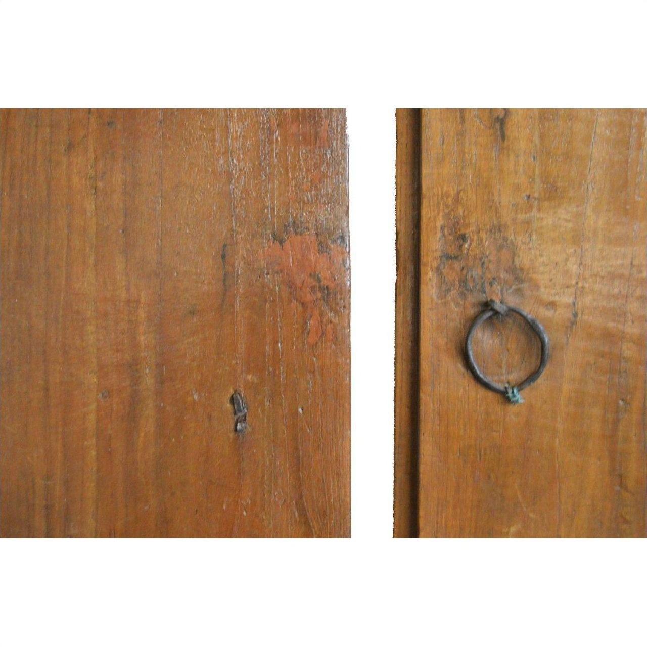 Close-up of brown wood antique Chinese doors with metal ring handle and natural patina, vertical gap visible.