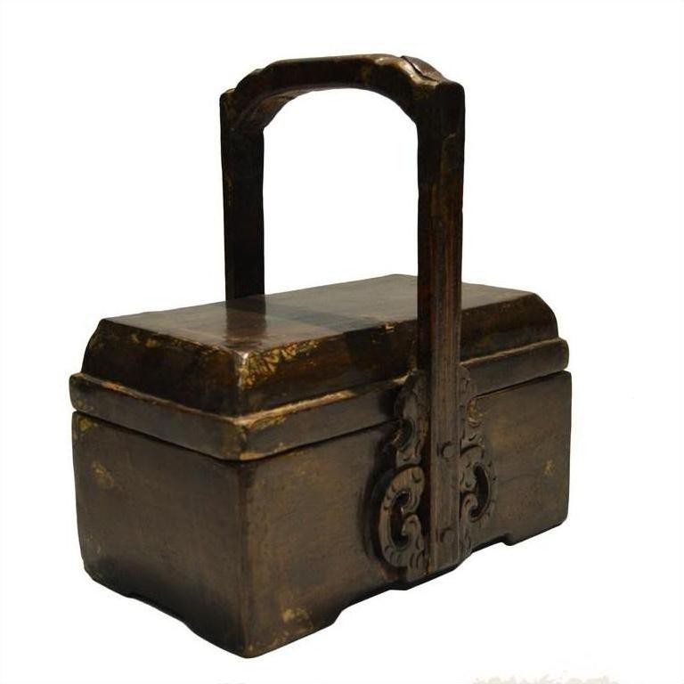 Brown wooden Chinese dowry box with tall ornate handle and carved details, close-up view.