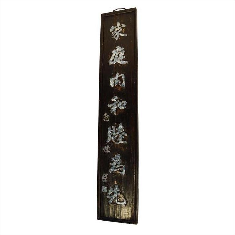 Close-up of antique Chinese enamel sign with white calligraphy on a dark vertical background.