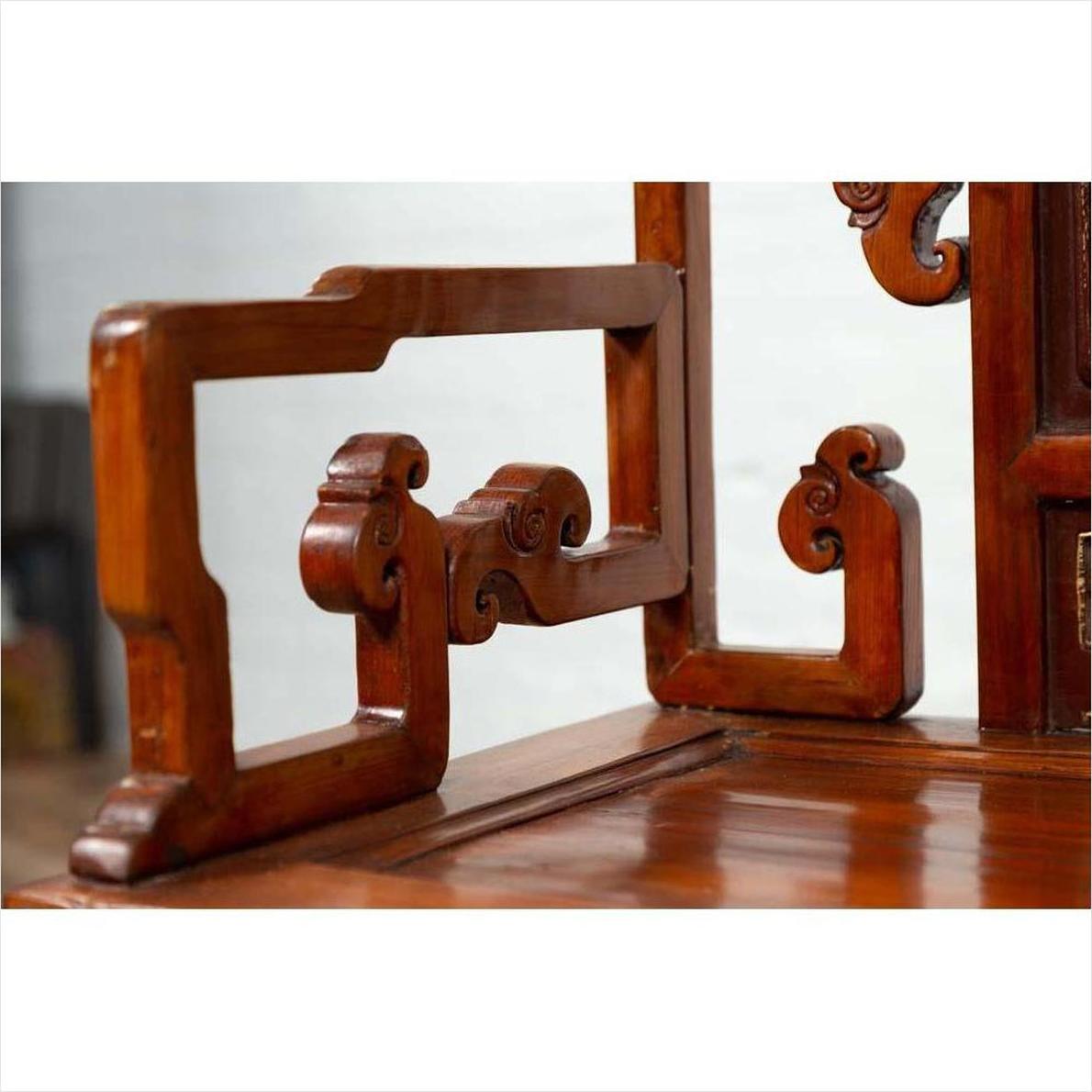 Close-up of brown wood armrest with ornate carving and natural patina on an antique Chinese chair.