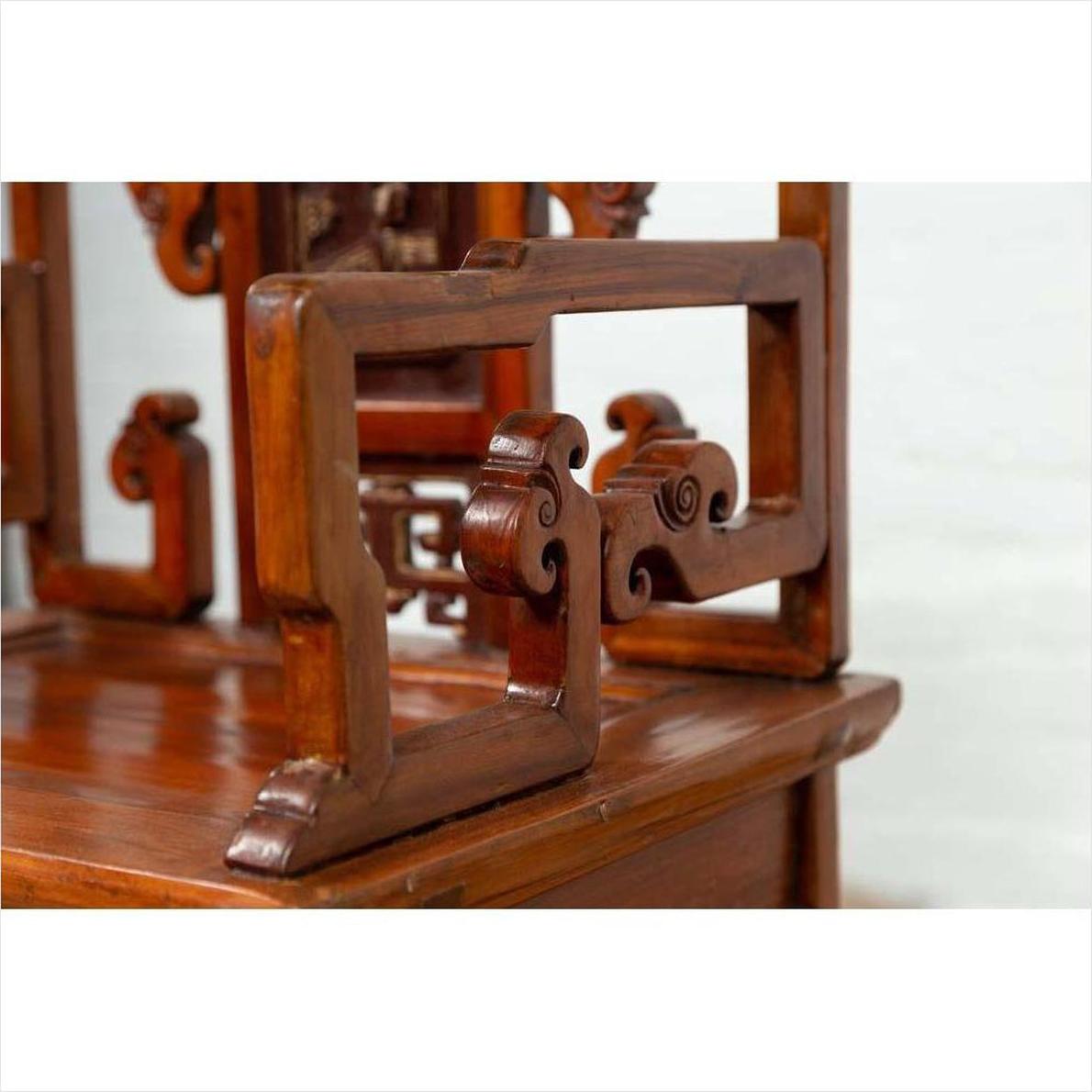 Close-up of brown wood hand-carved chair with scrollwork and natural patina, antique style.