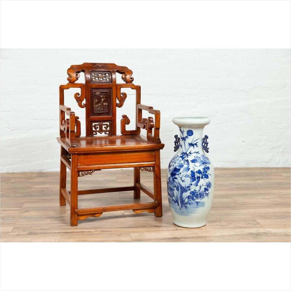 Brown wood hand-carved Chinese chair with natural patina on wooden floor next to large ceramic vase indoors.
