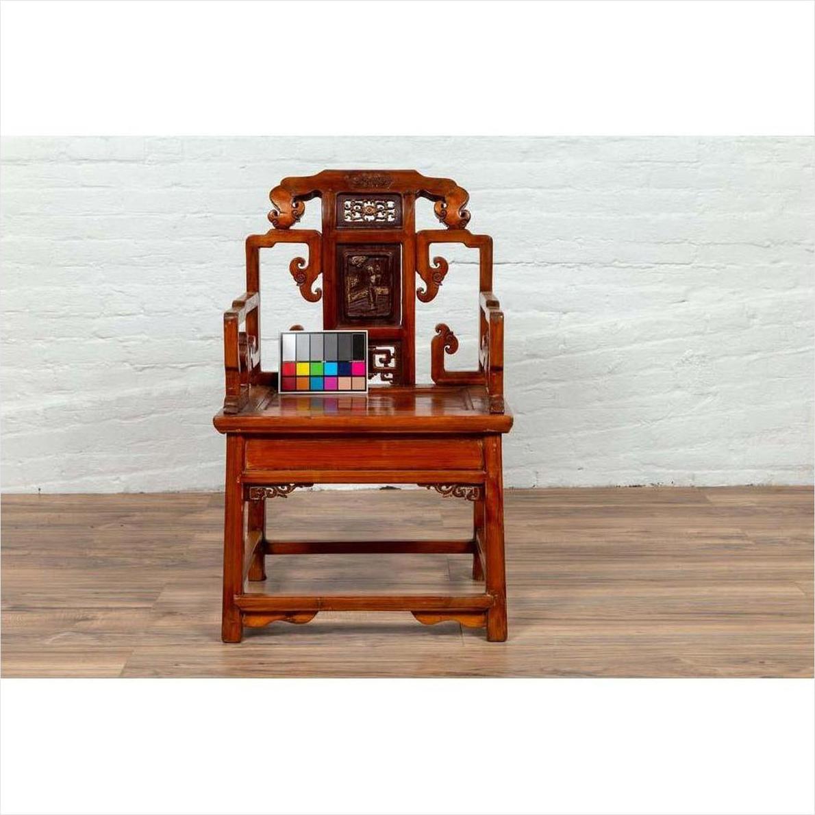 Natural wood chair with hand-carved details, wood patina, on wooden floor by white brick wall, color card on seat.