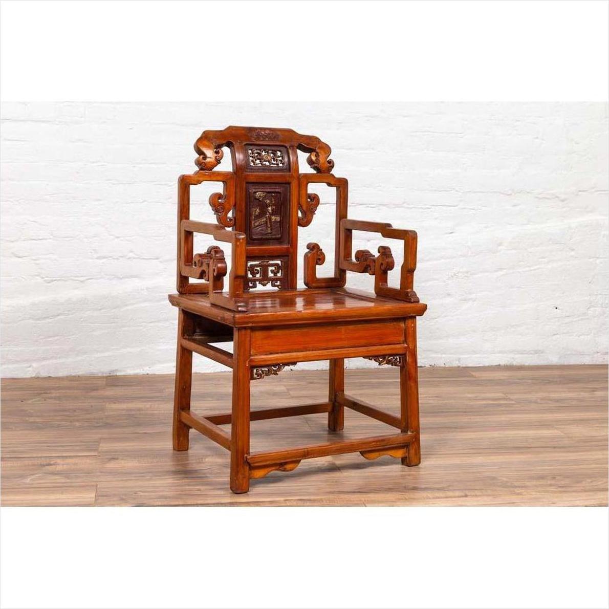 Brown wood hand-carved antique Chinese chair with natural patina on wood floor, white brick wall background.