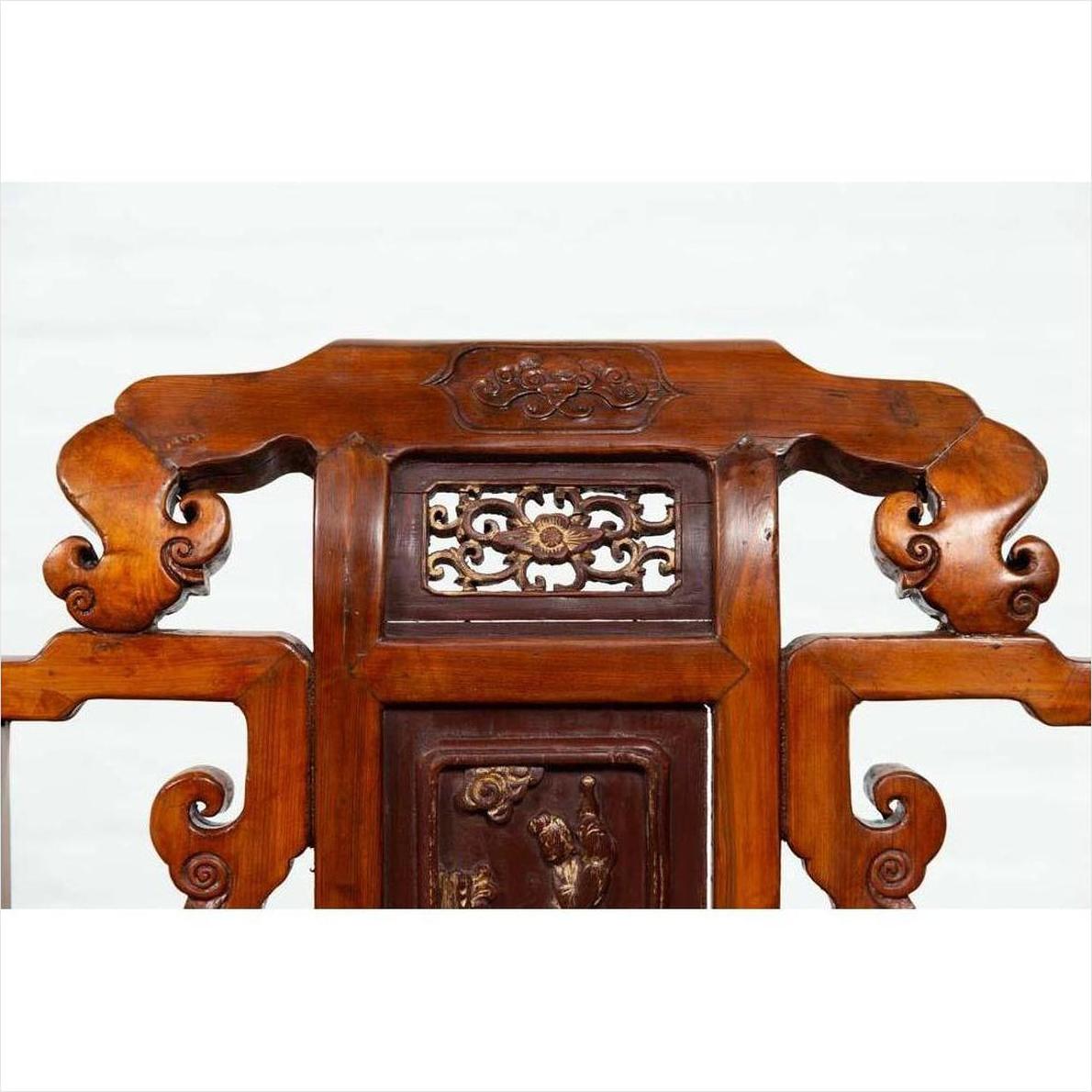 Brown wood hand-carved chair with ornate scrolls and intricate patterns, natural patina, indoors.