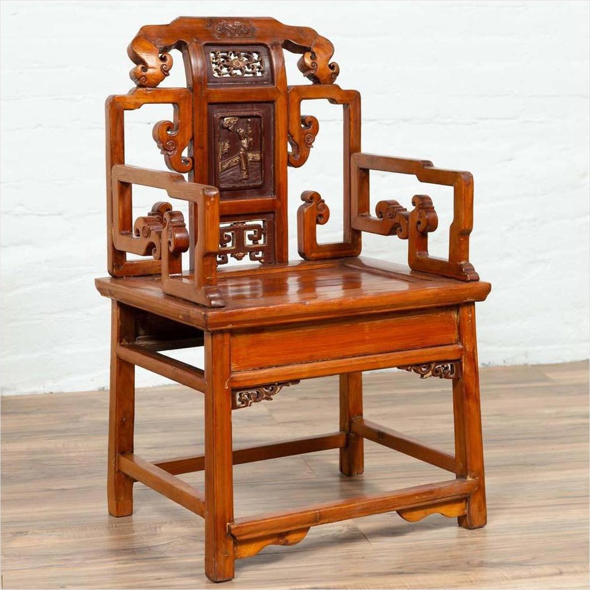 Brown wood hand-carved chair with natural patina on a wooden floor against a white wall indoors.