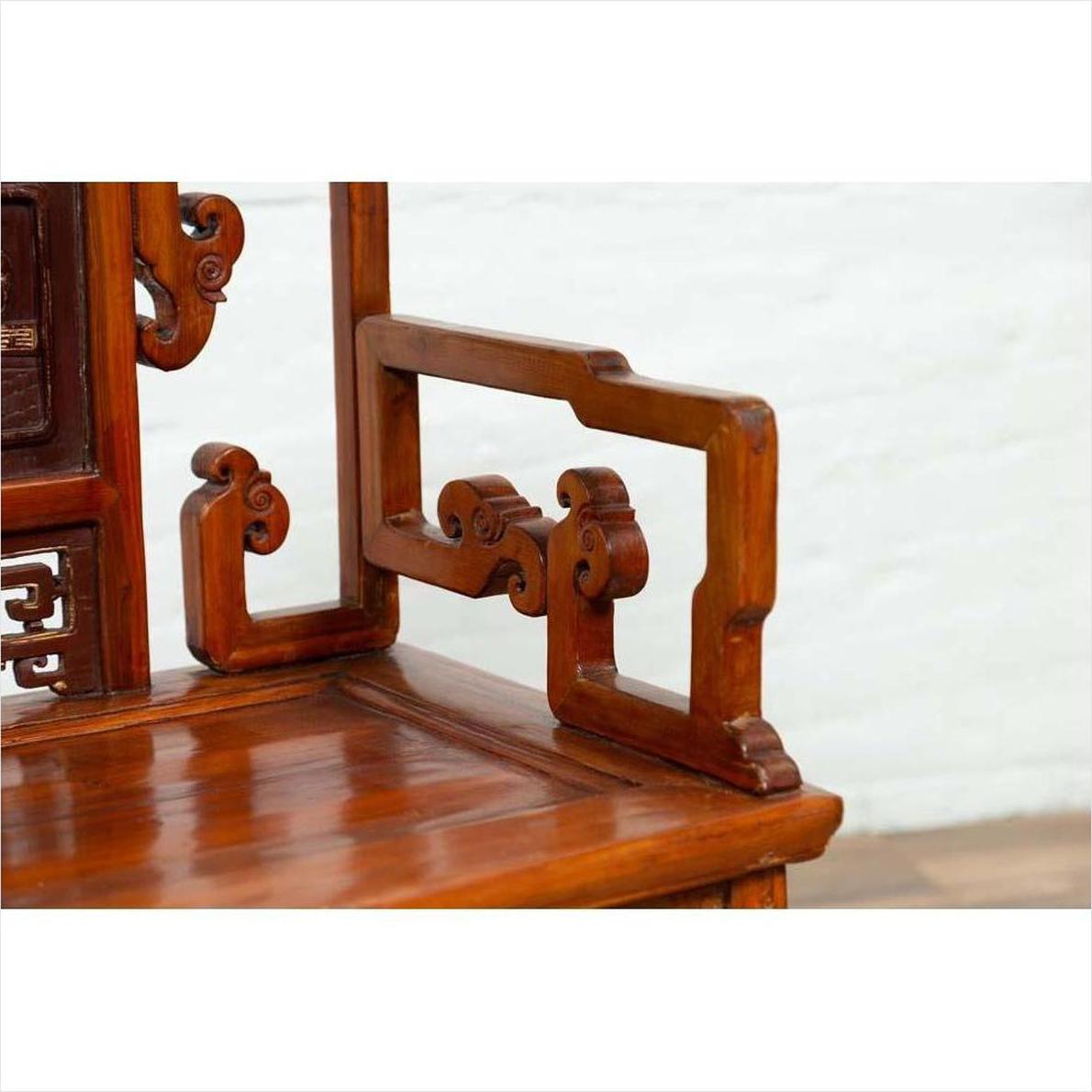 Close-up of brown wood chair with hand-carved intricate patterns and natural patina finish.