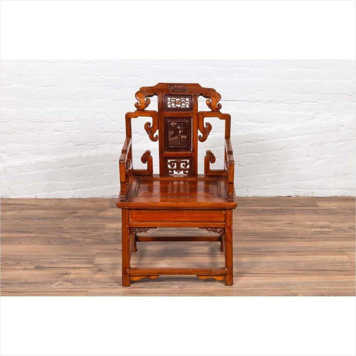 Brown wood hand-carved chair with natural patina on a wood floor in front of a white brick wall indoors.