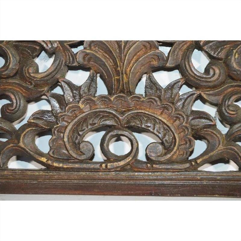 Brown lacquered rosewood wall plaque with symmetrical hand carved Chinese floral and leaf patterns, close-up.