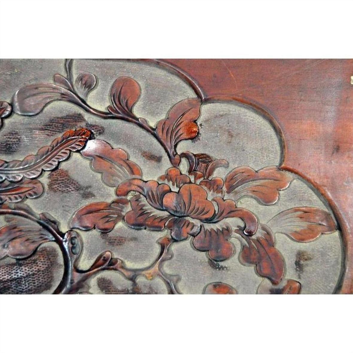 Reddish-brown and gray lacquer rosewood wall plaque with hand-carved floral design, close-up view.
