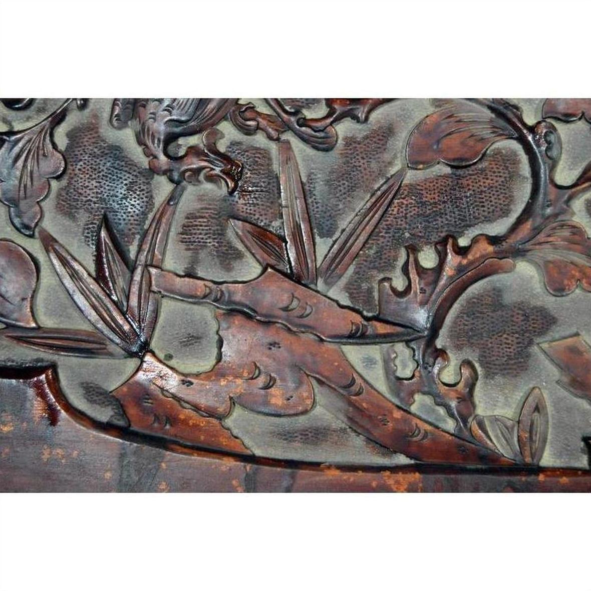 Close-up of dark rosewood lacquered wall plaque with hand-carved bamboo stems and leaves, antique Chinese design.