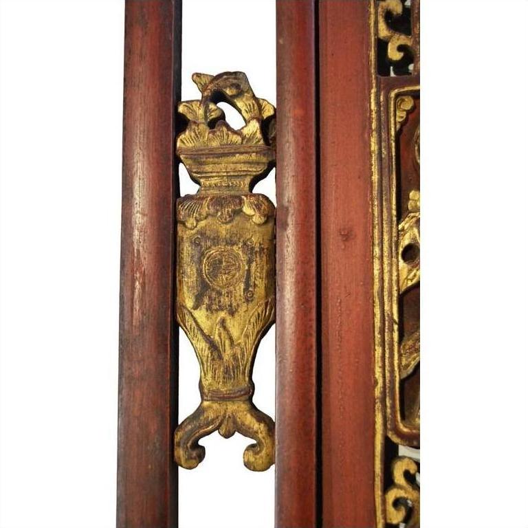 Close-up of gold gilt scrollwork on antique Chinese wooden architectural panel with multi-figure scene decoration.