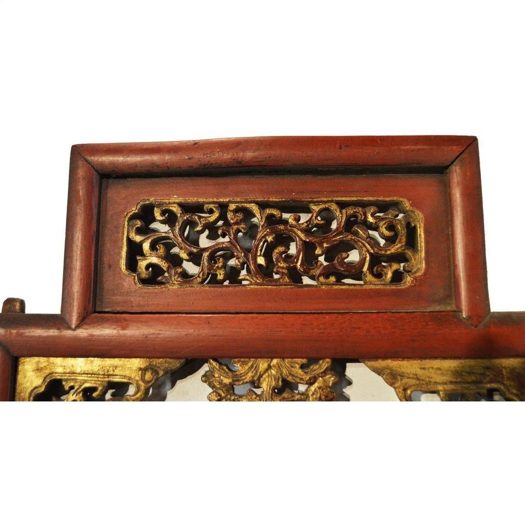 Close-up of red lacquer and gilt wood antique Chinese carved panel with intricate courtyard scene relief carvings.