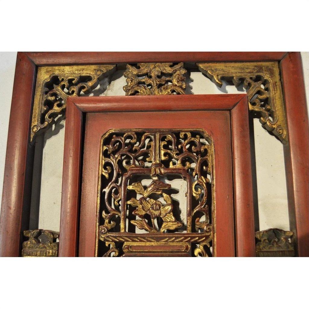 Red and gold carved wood Chinese panel with courtyard scene, ornate floral patterns, and gilt relief details.