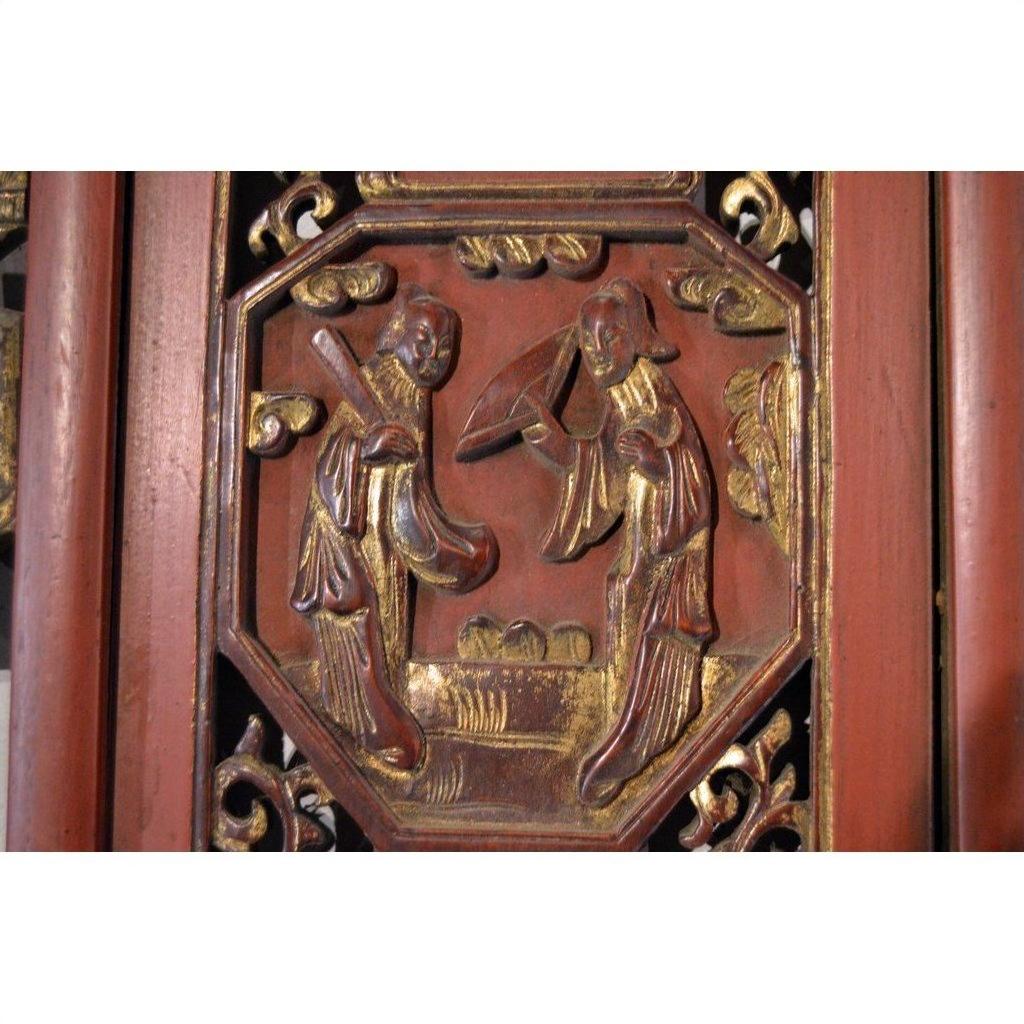 Red gilt wood Chinese carved panel, close-up of two figures in traditional dress, bordered by ornate decorative patterns.