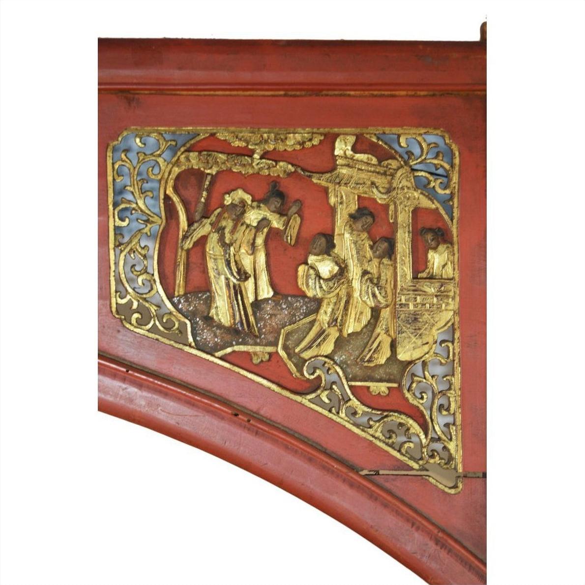 Red wood sign with gold relief of three Chinese figures in traditional dress, carved details visible on the panel.