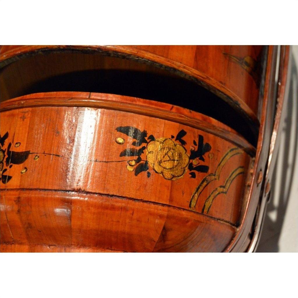 Close-up of a bamboo basket with hand painted yellow flower and black leaf motifs.