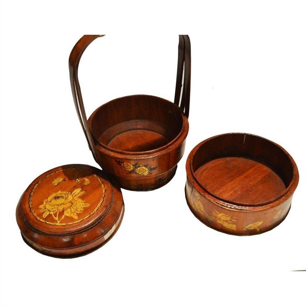 Close-up of three round antique Chinese bamboo baskets with hand painted floral designs, two lids placed beside them.