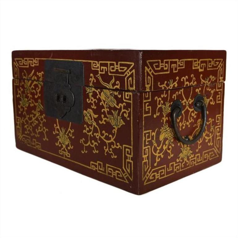 Close-up of red and gold lacquer antique Chinese box with central latch, stylized bird design, ornate handles.