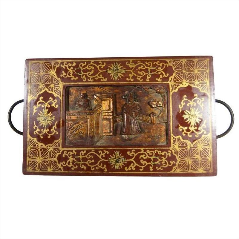 Black lacquered wood box with central latch and stylized birdwork design, close-up.