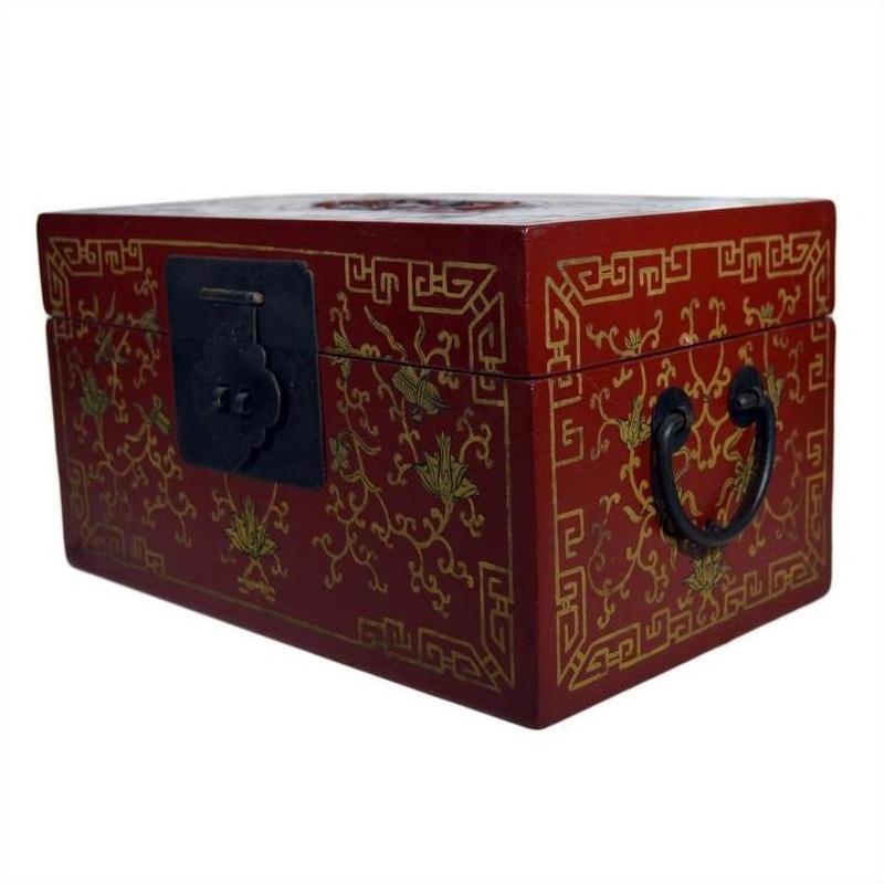 Red Chinese lacquer box with gilt vine and phoenix motif, black handles, and decorative black latch, close-up view.