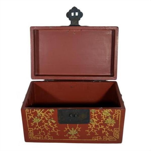 Red lacquer box with gold floral inlay, ornate black latch, on a plain surface.