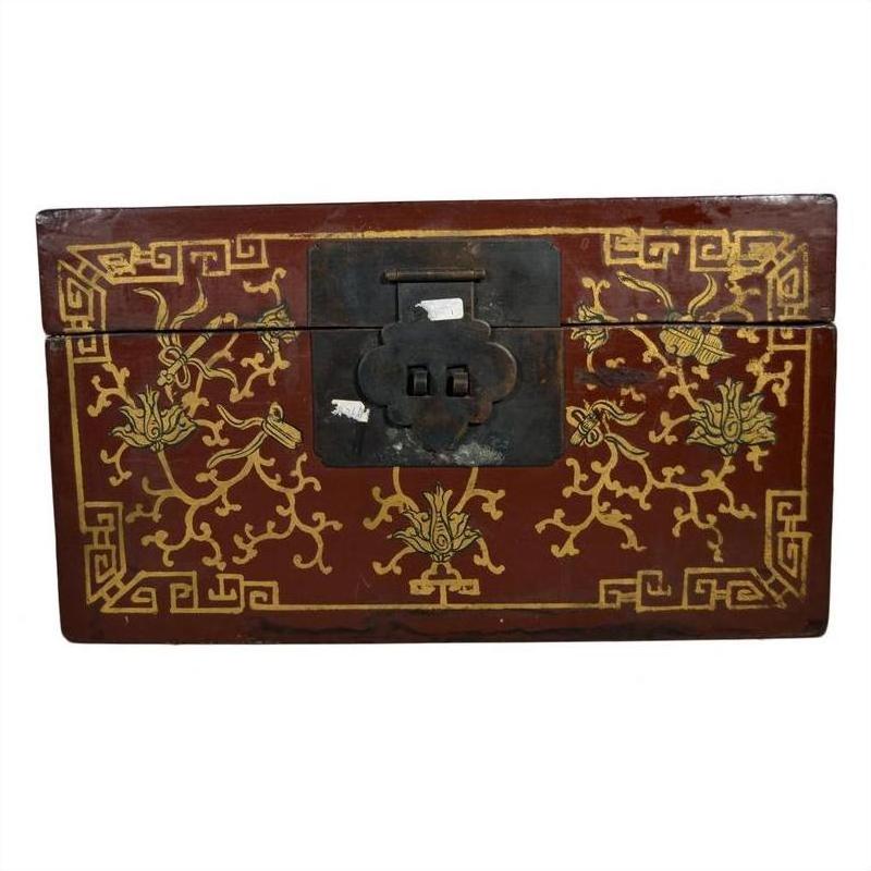 Close-up of red and gold Chinese lacquer box with raised scene on lid and large black metal front latch.
