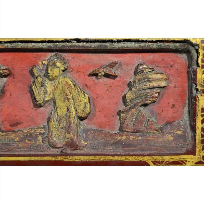Red and gold lacquer box with hand-carved figure in yellow robe, bird, and rock on raised top.