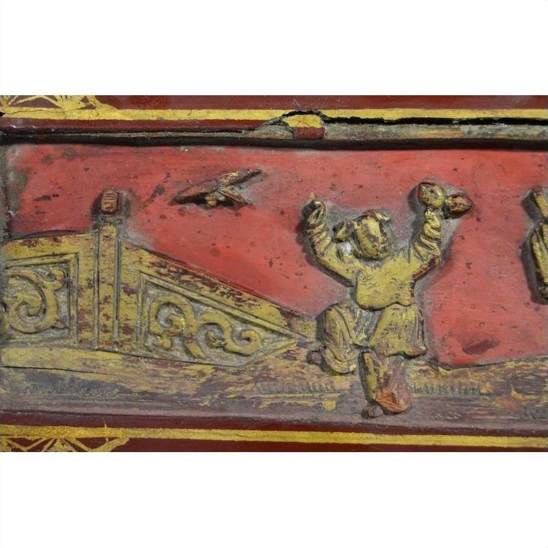 Close-up of red and gold lacquer box with ornate raised design, antique finish.