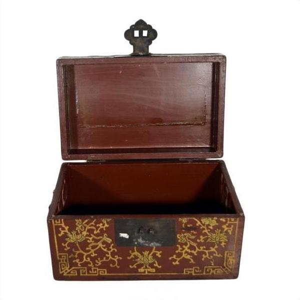 Red and gold lacquered box with raised scene on top, ornate floral patterns on front and sides, photographed indoors.