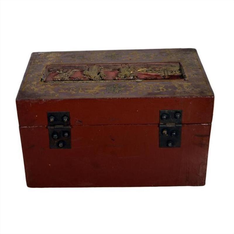 Red and gold lacquer box with raised top scene and ornate vintage details, on plain background.