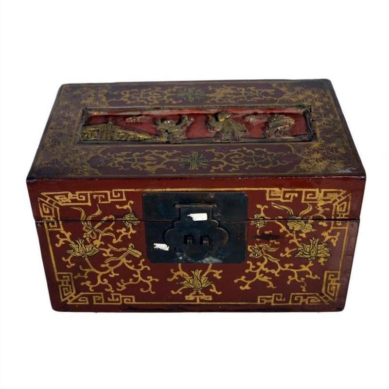 Red and gold lacquered Chinese box with raised top scene and old metal latch, close-up view.