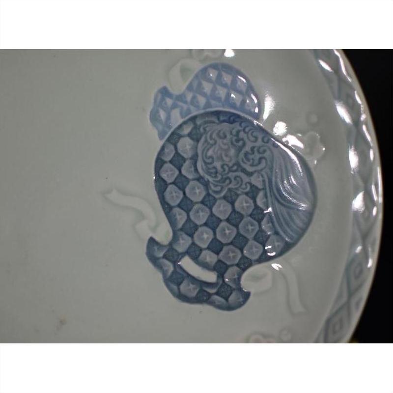 Close-up of blue and white embossed porcelain plate with hand painted Chinese patterns on white background.