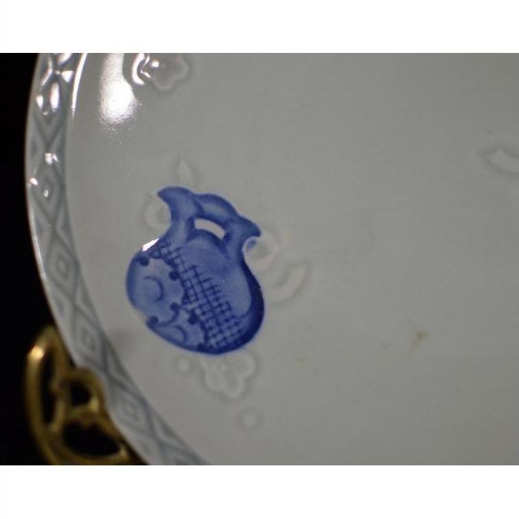 Blue and white porcelain plate with hand-painted pitcher motif and embossed rim, close-up view.