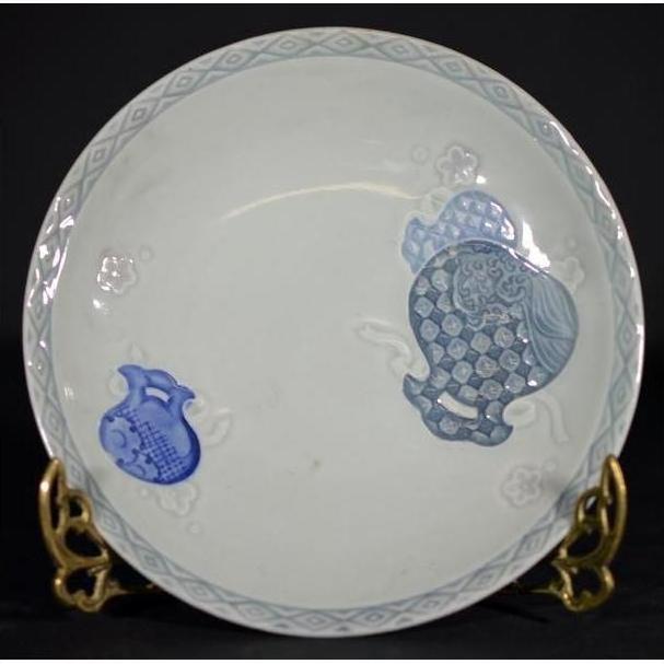 Close-up of an antique Chinese porcelain plate with hand painted blue fish, embossed details, on ornate gold stand.