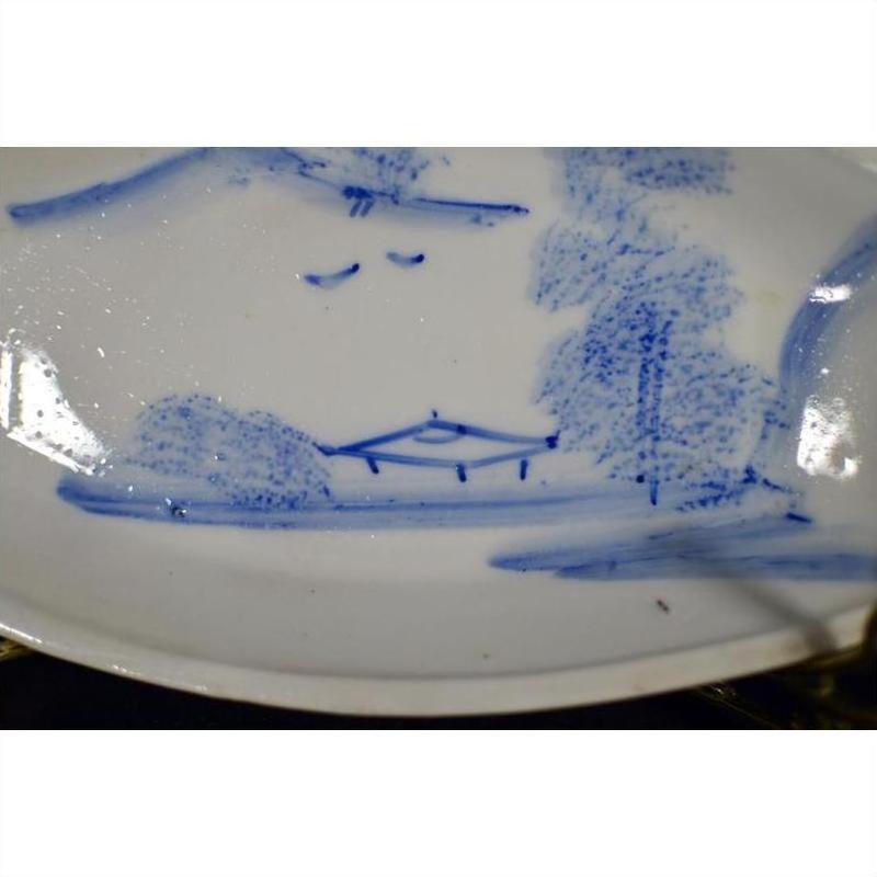 White ceramic boat-shaped dish with misty landscape design and two flying birds, close-up.