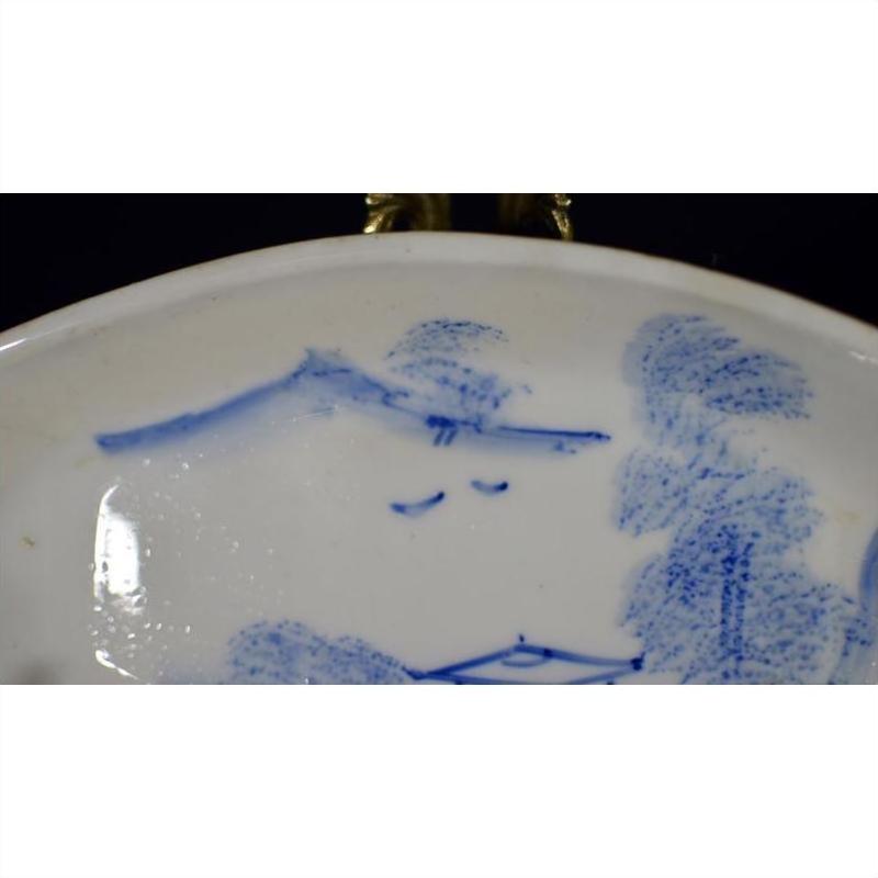 Close-up of antique ceramic boat-shaped dish with painted misty landscape and two flying birds design.