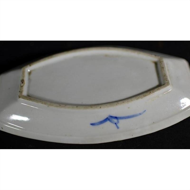 Close-up of blue and white porcelain boat-shaped dish with hand-painted mark and rectangular foot rim.