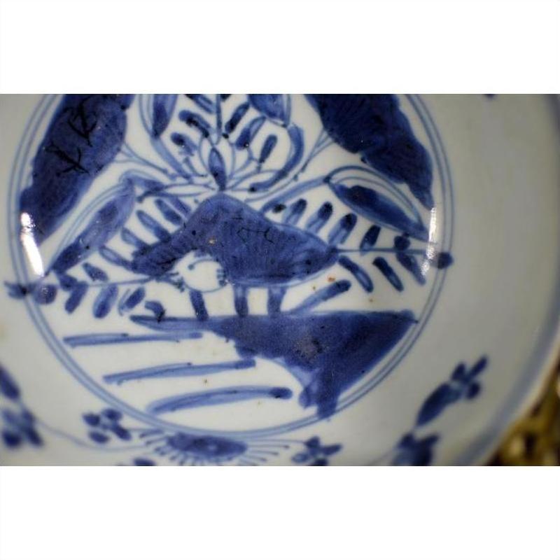Blue and white porcelain dish with foliate hill motif and rustic brushwork, antique Asian style, close-up.