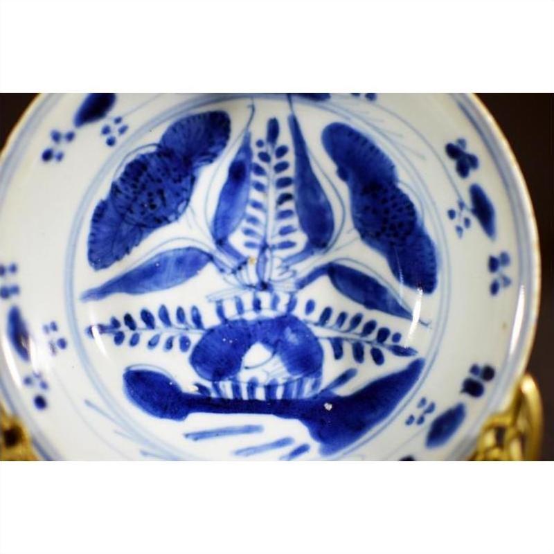 Blue and white porcelain dish with antique botanical spray pattern, radial layout, close-up top view.