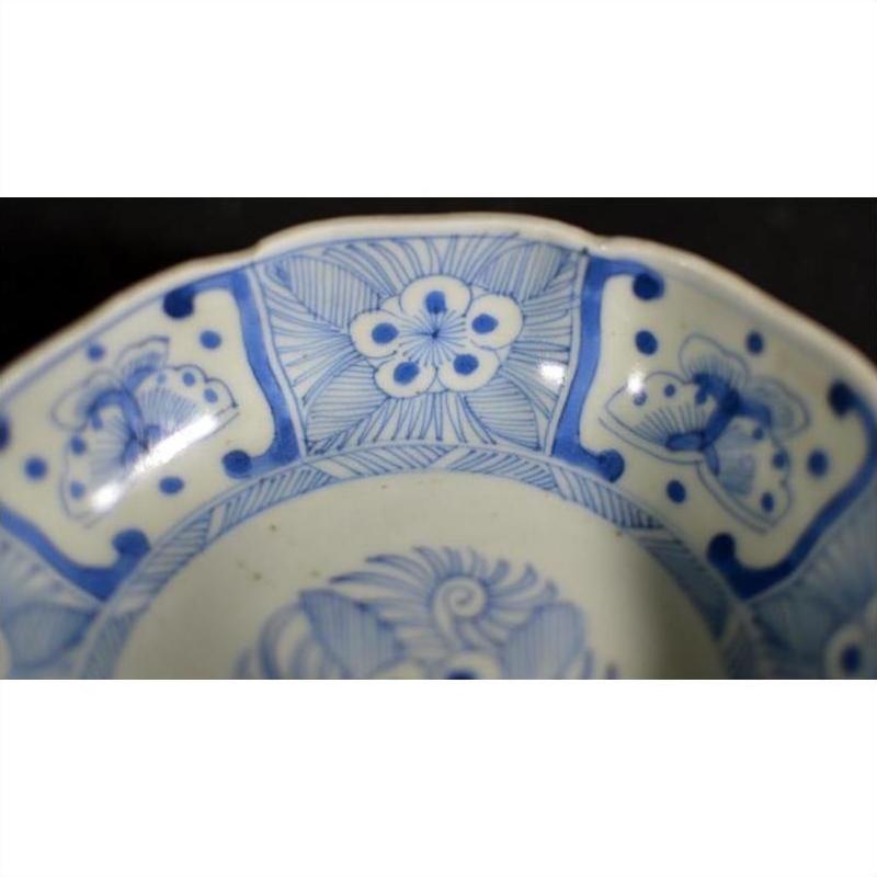 White porcelain bowl with butterfly cartouches and petal-shaped rim, antique Chinese style, close-up view.