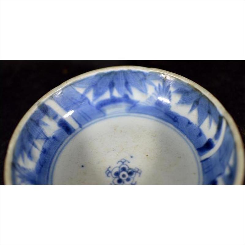 Blue and white porcelain dish with rosette medallion, alternating floral and geometric panels, close-up view.